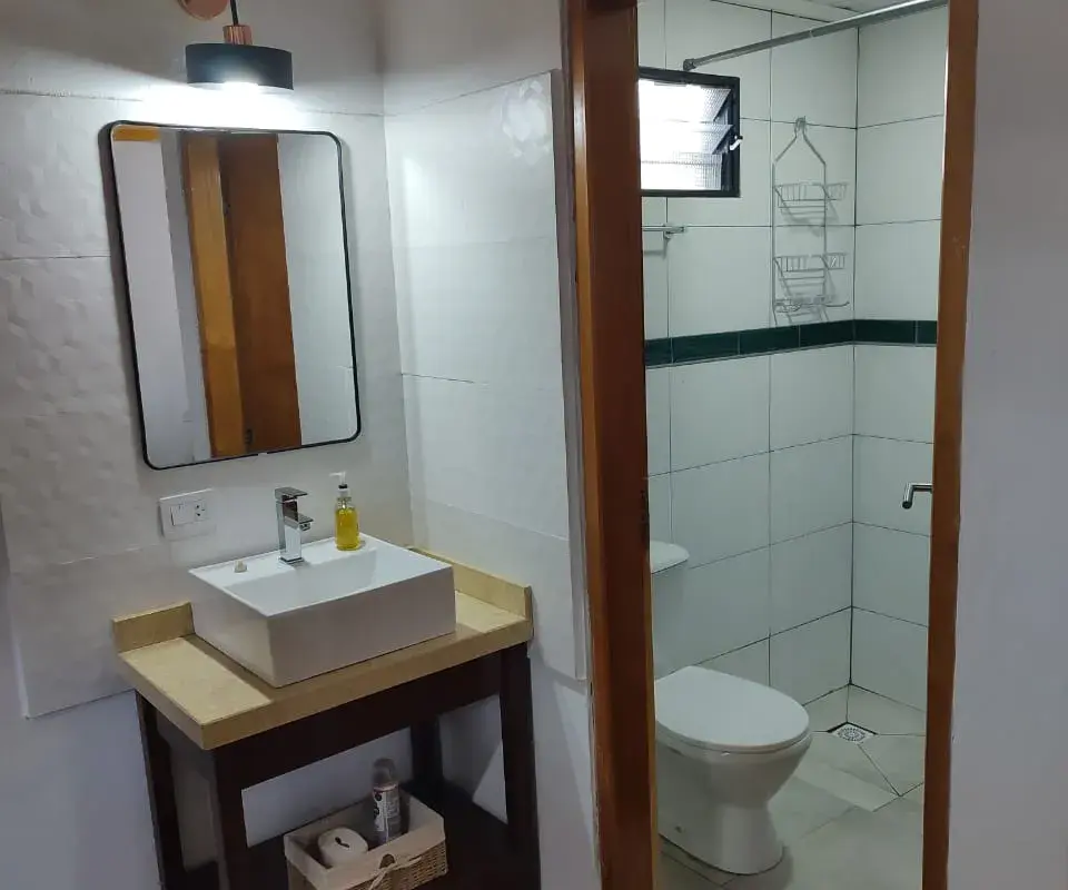 Baño completo con vanitory de madera, espejo y ducha en loft Yvyra, Puerto Iguazú