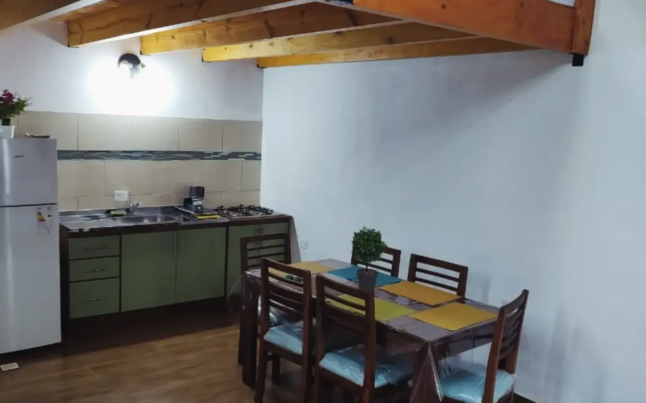 Cocina equipada con heladera, anafe y comedor para 6 personas bajo entrepiso de madera en Yvyra, Puerto Iguazú