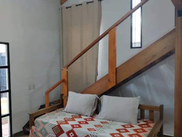 Dormitorio planta baja con sofá cama y escalera al entrepiso en loft Yvyra